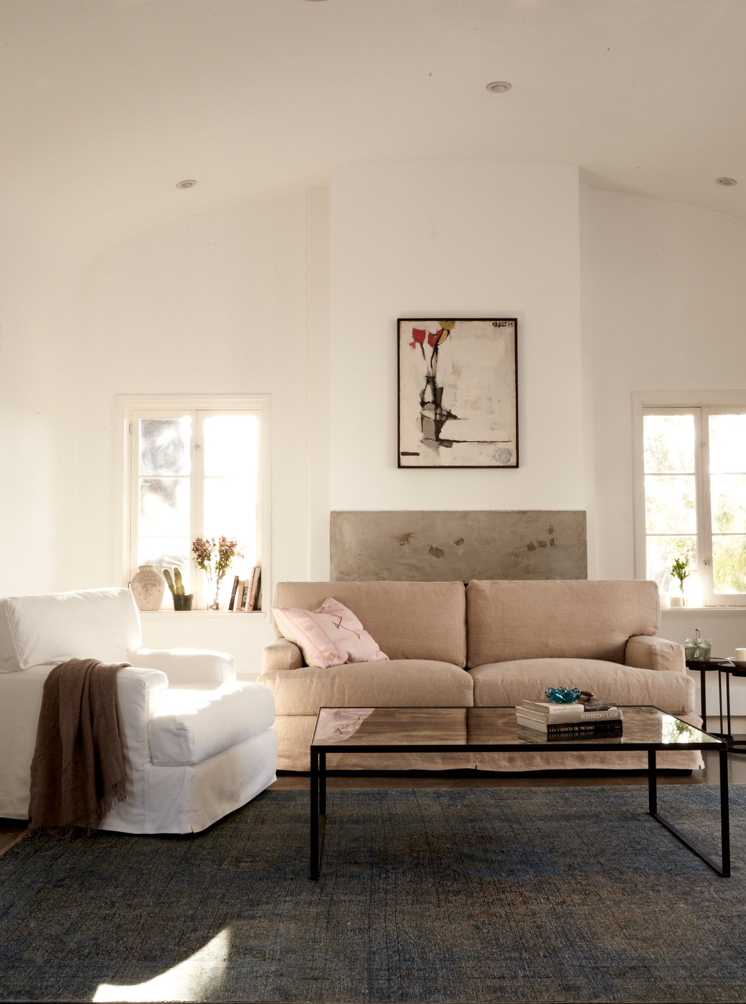  白色牛仔布椅子，旁边是浅色沙发和玻璃咖啡桌. 背景是白色的墙壁和挂在墙上的一幅画. 