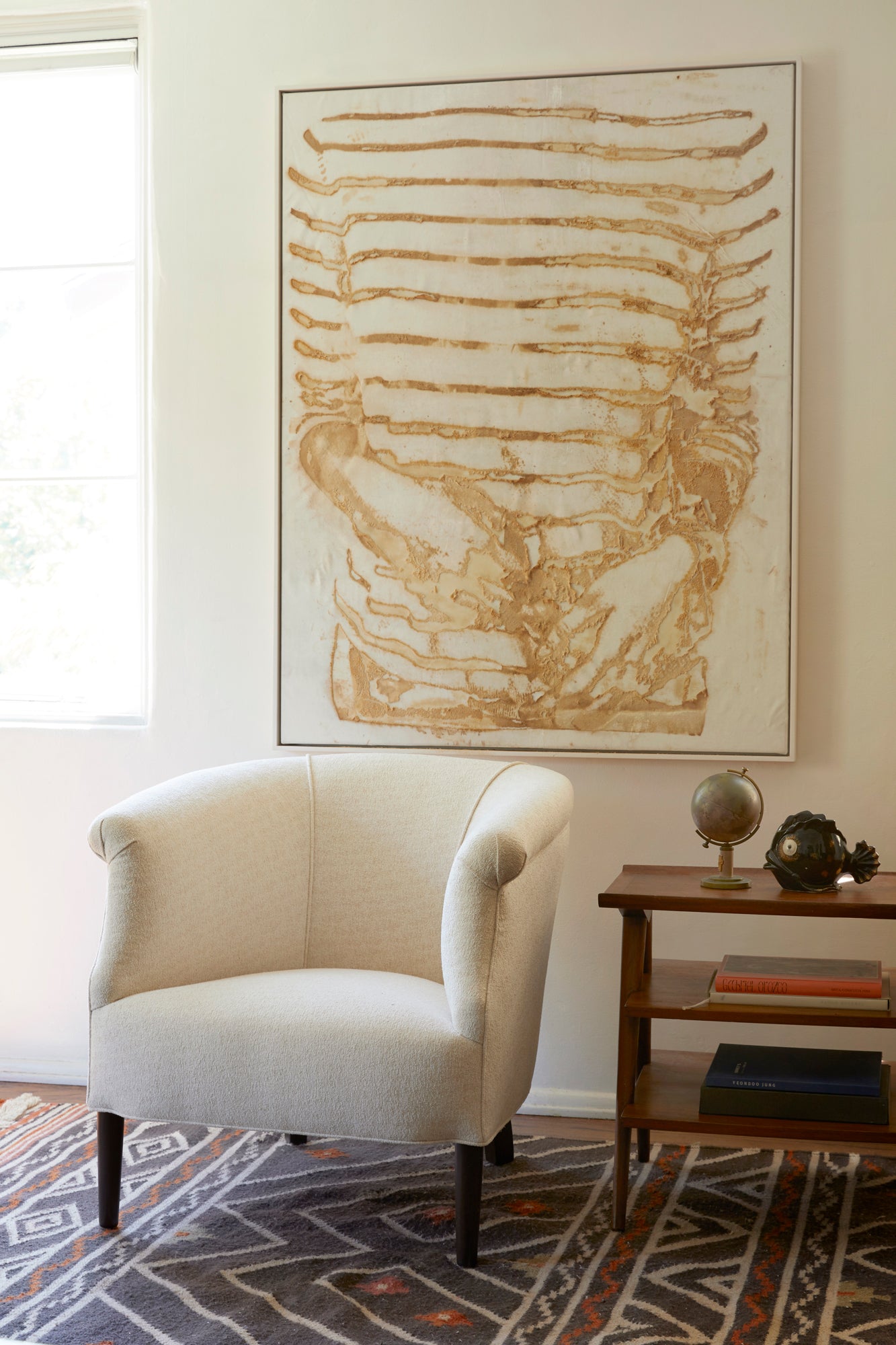  在Lucerne Vanilla的椅子旁边的木桌. 背景是一面挂着抽象画的白色墙壁. 