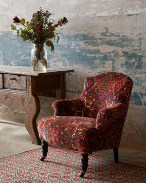  用一种织物做的椅子，旁边是一张木桌，上面有花. 背景是一面混凝土墙. 穿着一种面料拍的照片. 