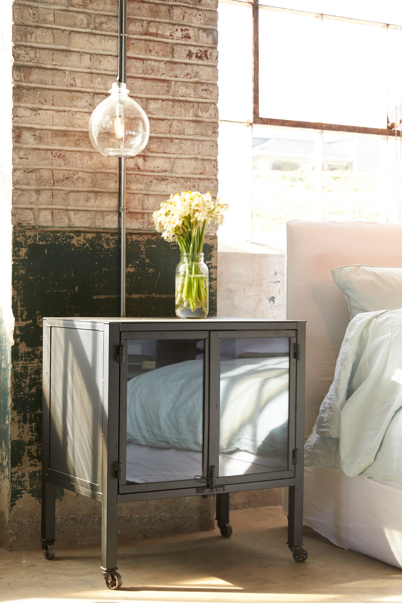  Isaac night stand in black finish with small jug lamp in clear finish. Corner shot of slipcovered bed in white finish.  