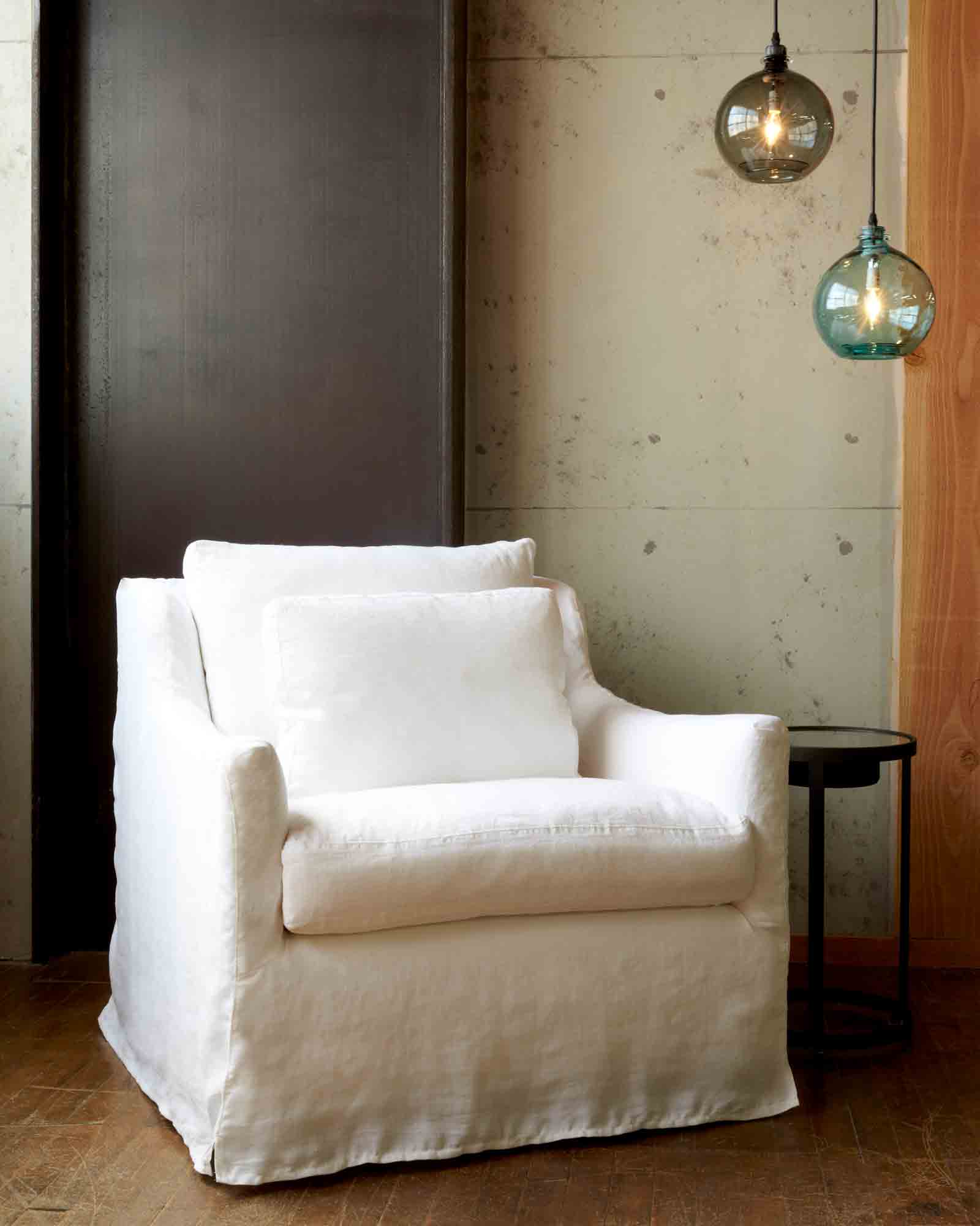  椅子在奥的斯怀特旁边的金属边桌. 背景是一面白色的墙，墙上挂着两盏水罐灯. 