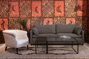  Lucerne Vanilla的椅子，旁边是深色沙发和茶几. 背景是一面鲜艳的红色图案墙. 