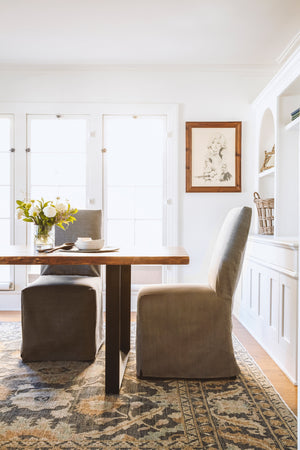  帕森斯的餐椅在Molino Ash旁边的一张木餐桌. 背景是白色的房间，木框和玻璃门. 