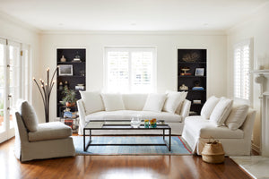 Seda椅子在洛根银旁边的白色沙发，一个金属咖啡桌，和黑色落地灯. 背景是一个带有日常家居装饰的白色房间. 