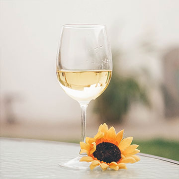 verre de vin blanc posé sur une table avec une fleur de tournesol