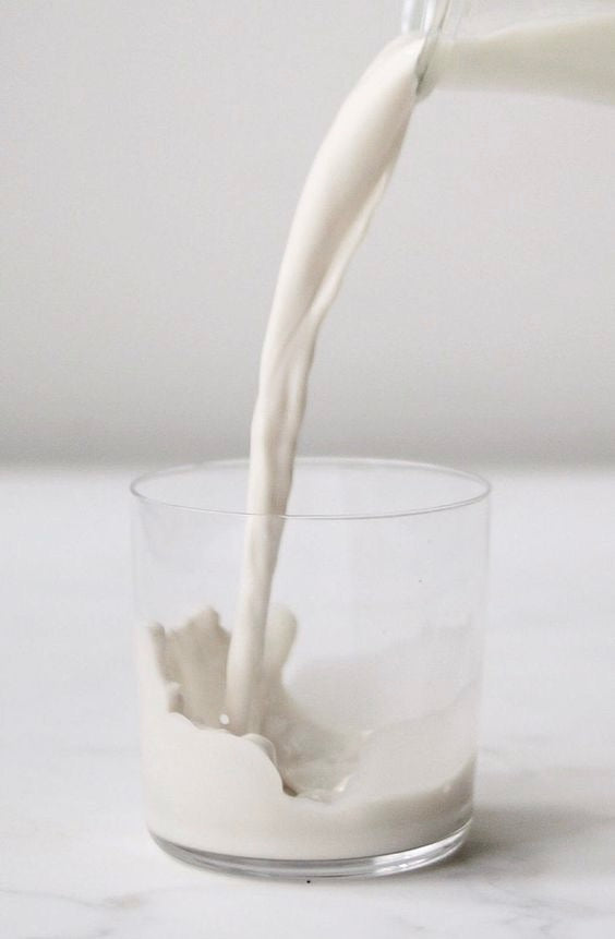 Image of Fresh homemade almond milk being poured into a glass. 