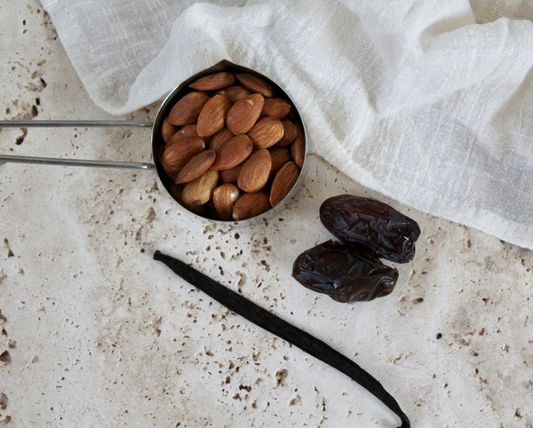 Image of Home made almond milk ingredients spread out on a travertine surface. 
