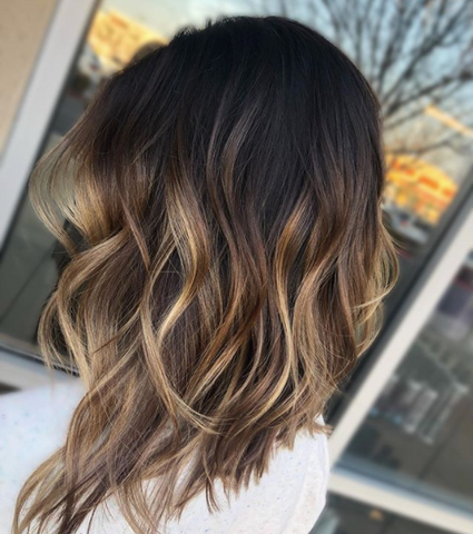 Person with a dark long bob with blonde balayage 