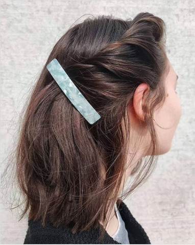 White woman with dark brown hair pinned with a turquoise hair clip
