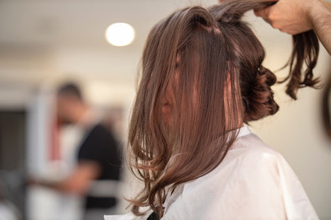 Woman with brown hair getting her hair done at a salon