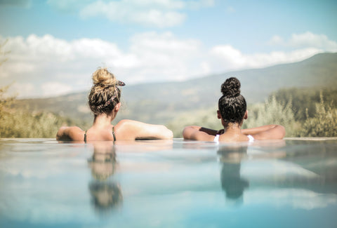 Two women in a swimming pool looking at the horizon.