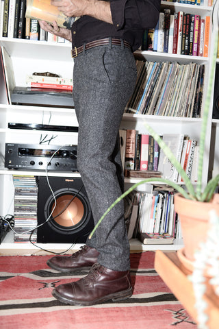 Cropped photo of Donegal tweed trousers on a model standing in front of a record player.