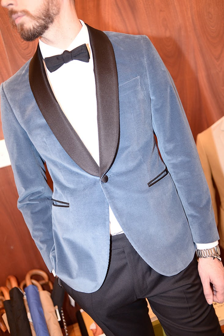 Model wears a blue corduroy dinner jacket with a white tuxedo shirt and black bowtie. 