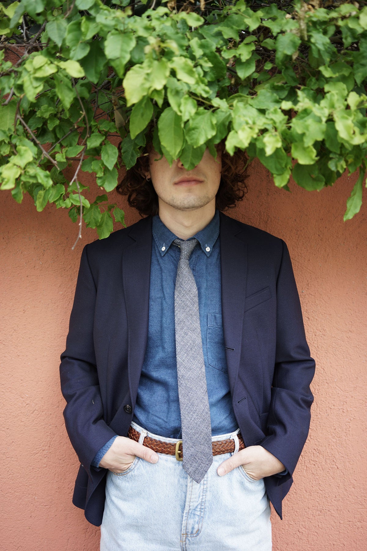 Model wears navy unstructured blazer over chambray shirt, with gray tie and jeans.