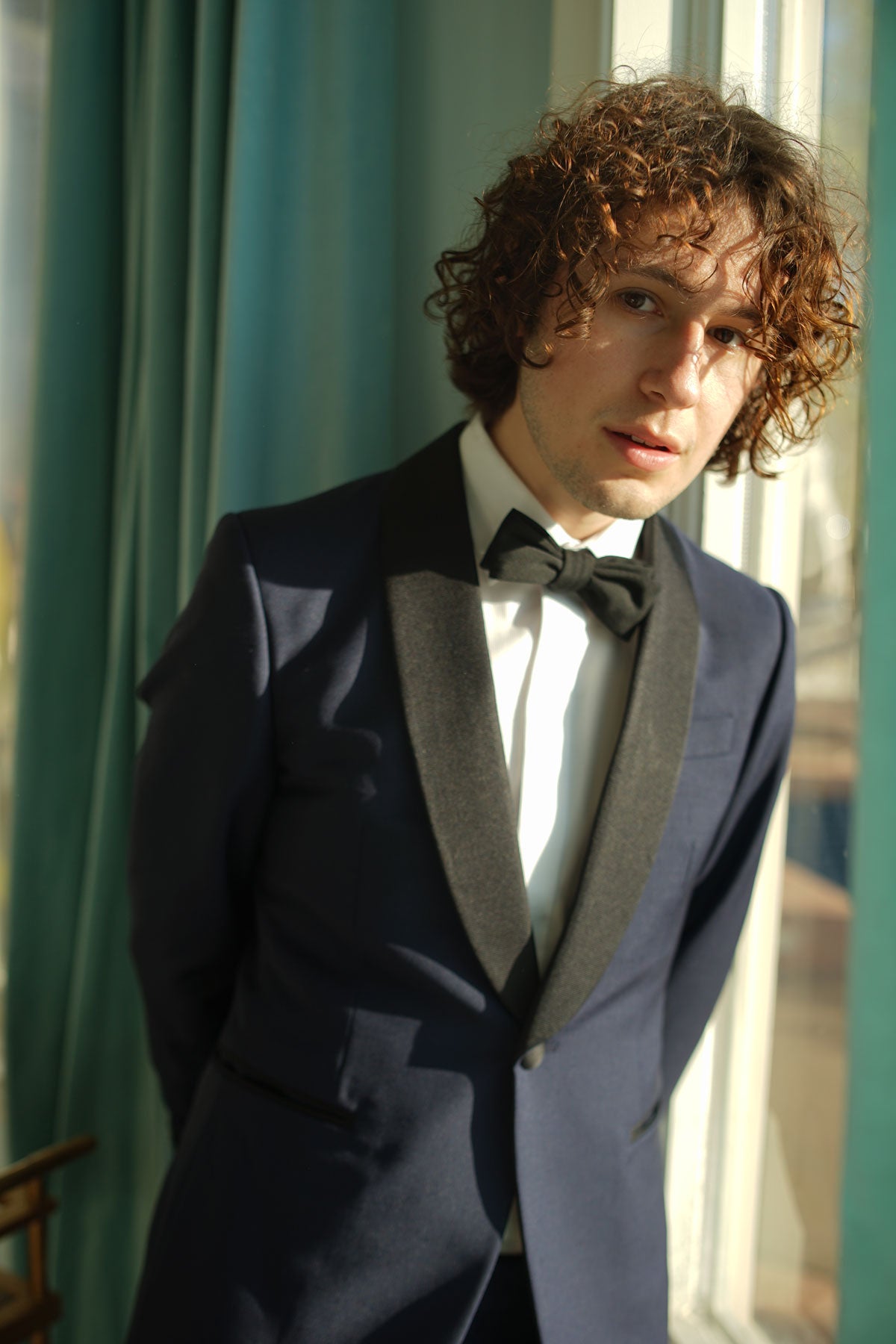 Close-up shot of model wearing navy tuxedo, white tux shirt, and black bowtie.