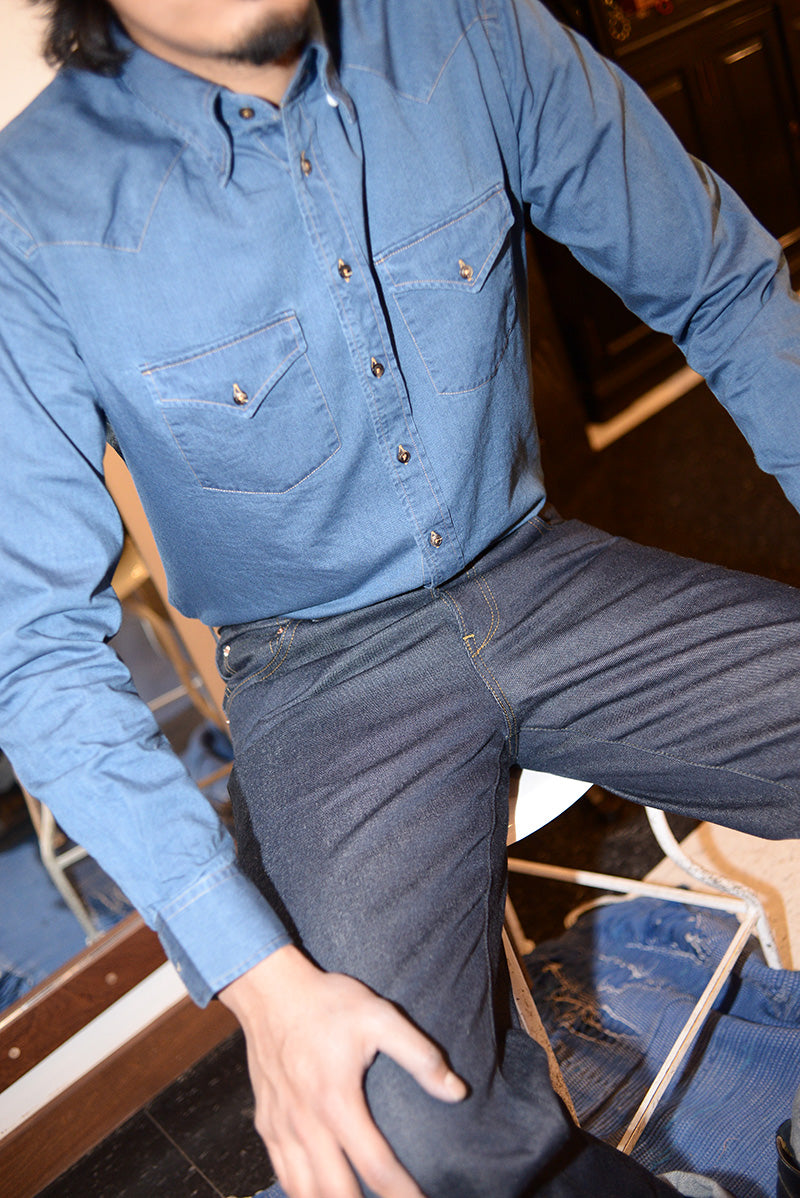 Close-up shot of model wearing denim jeans and a chambray western shirt. 