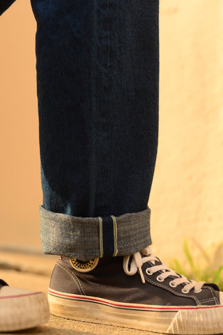 Close-up of a cuffed jean hem and a sneaker.