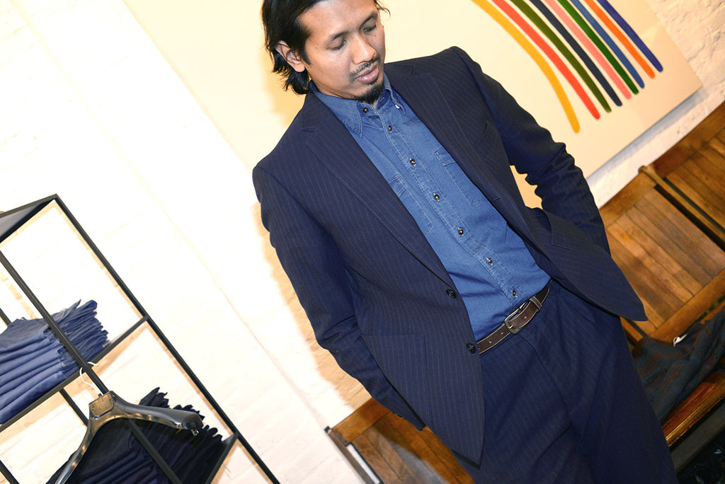 Model wears a navy pinstripe unstructured suit with a chambray western shirt. 