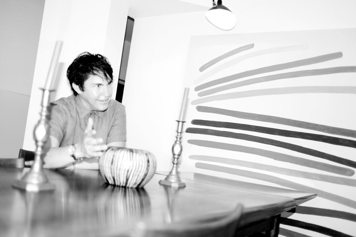 Black and white photo of Dave sitting at a table next to one of his paintings