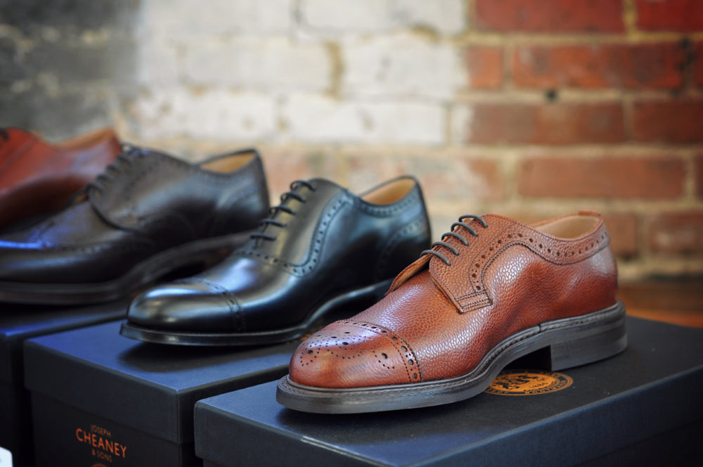 Close-up shot of four pairs of Cheaney dress shoes on top of their respective shoe boxes.