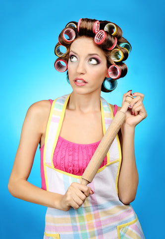 Housewife with curlers in her hair holding a rolling pin rolling her eyes