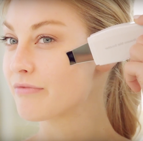 Blonde Woman Using the Ultrasonic Scrubber to smooth serum deeper into the skin.