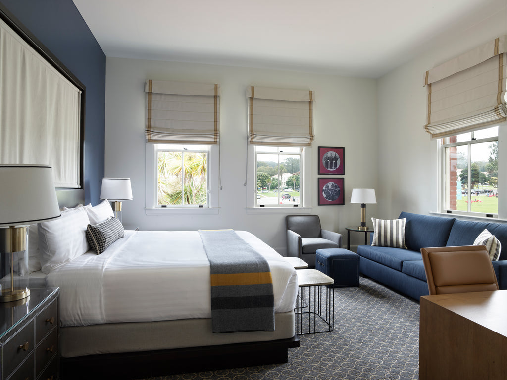 A guest bedroom at the Lodge at Presidio features a clean, well-made bed and a few other pieces stylish furniture.