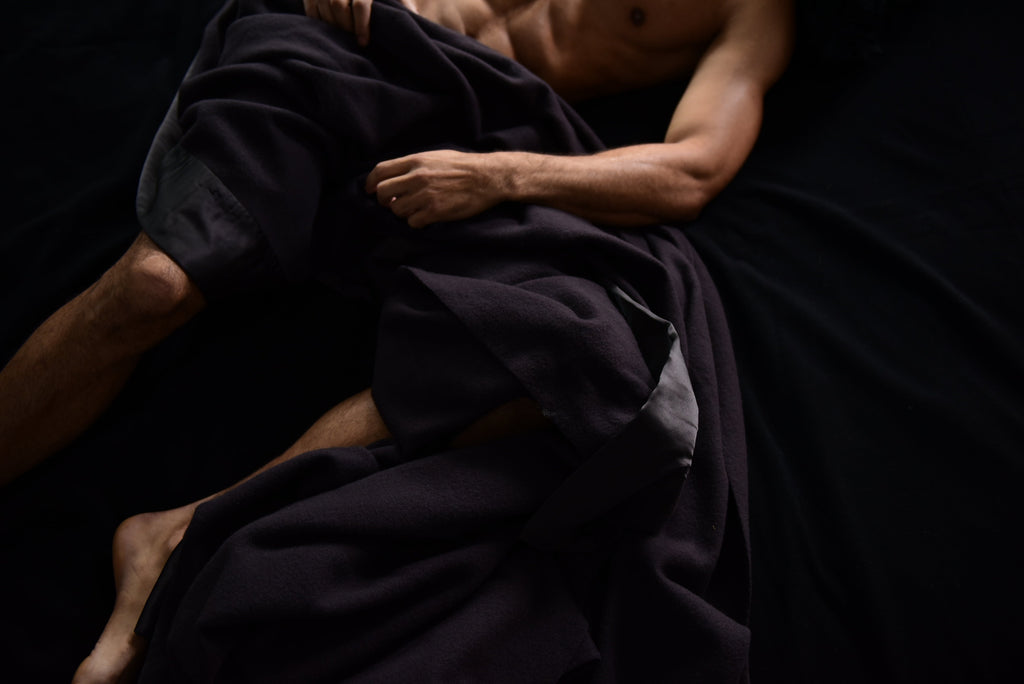 Man lying in bed with black as night henry luxury throw for bed
