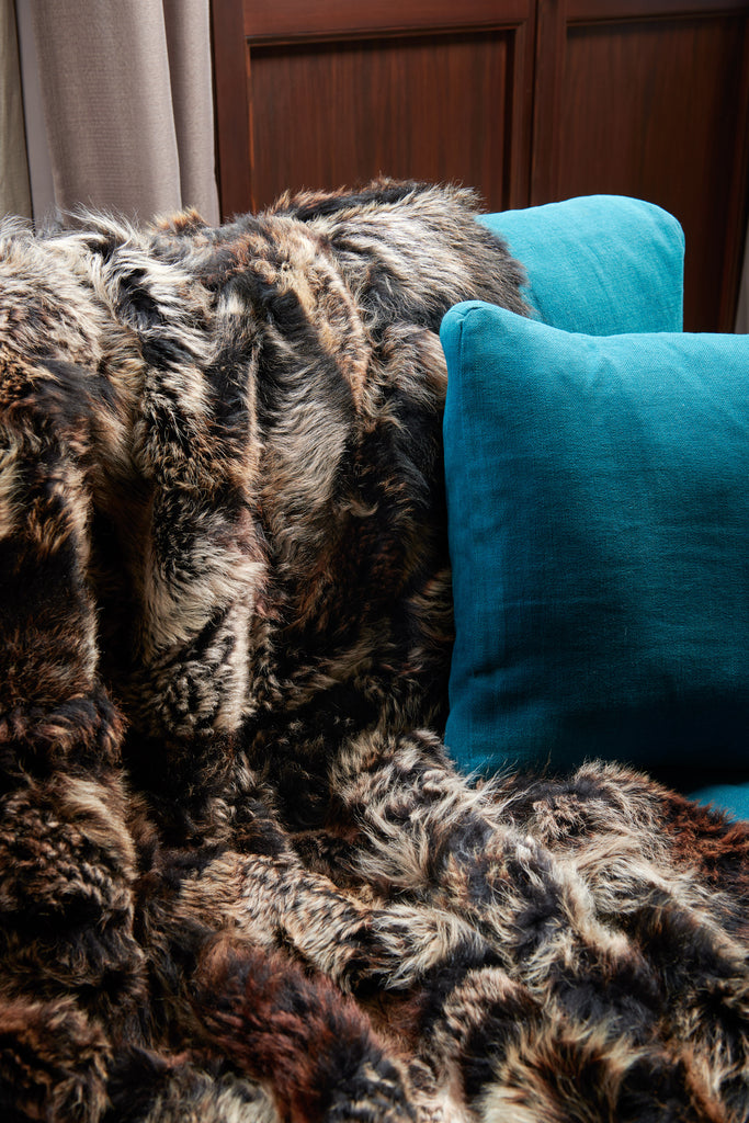 Close up of luxury real sheepskin fur blanket in truffle brown on couch