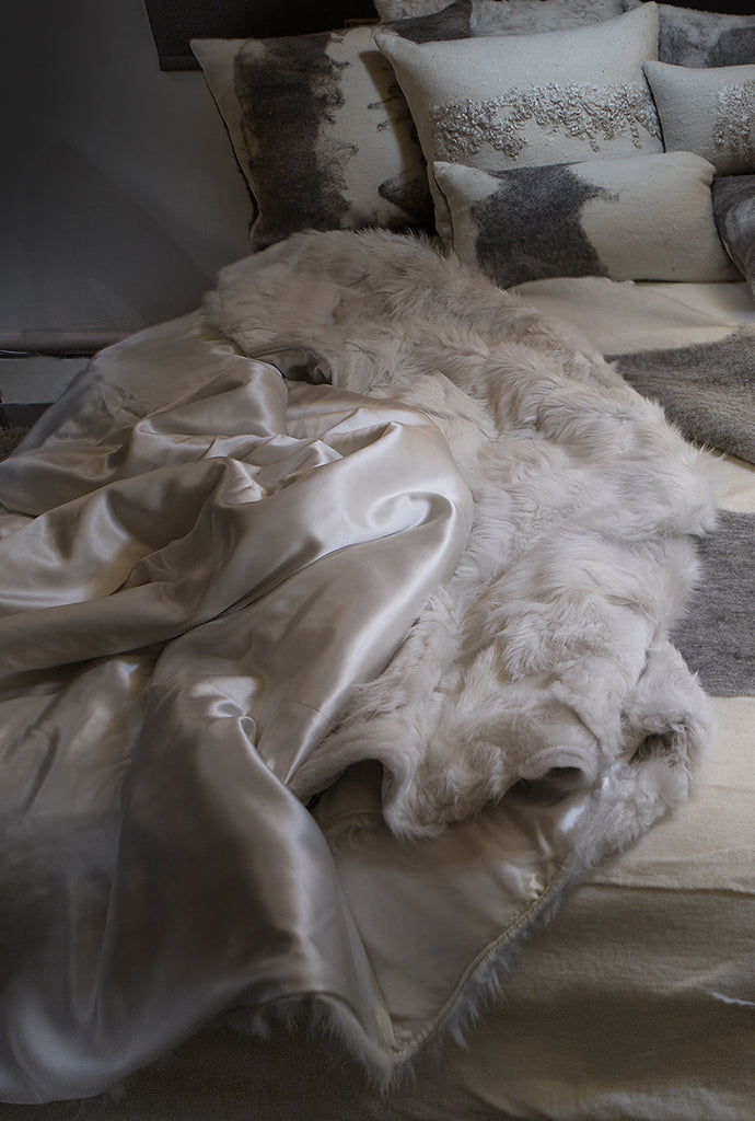 Luxurious real white fur blanket with pure silk lining lying in bed