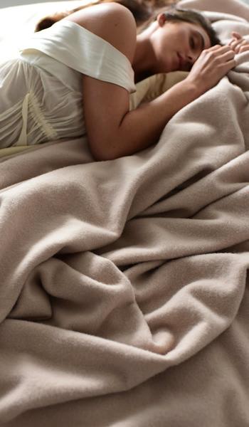 model in bed with hollywood ava luxury blanket in champagne beige