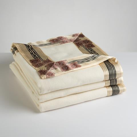 Now Voyager luxury throw blanket in white lying folded with rose motif pure silk border