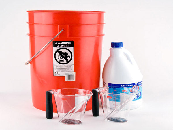 red bucket, two clear plastic measuring cups, and a bottle of bleach