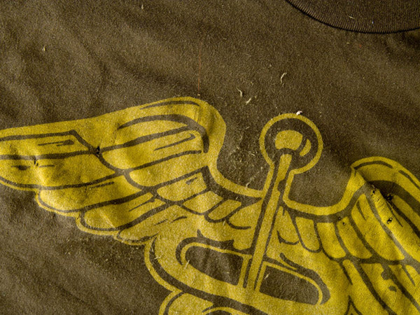 a close-up view of an olive green t-shirt that has been aged using sandpaper