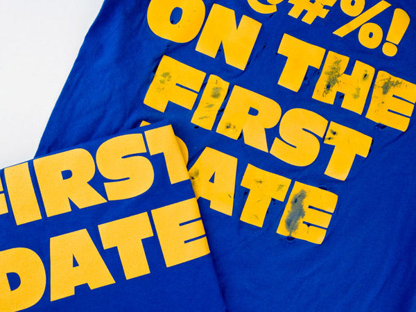 a blue t-shirt with yellow screenprinted text that has been scraped with sandpaper
