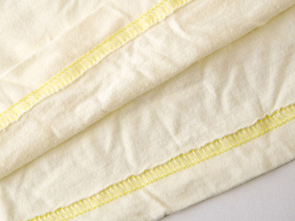 close up view of bleached yellow t-shirt that has stitching using yellow thread