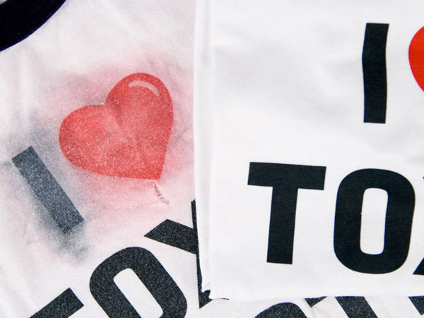 close up view of two i heart toxic waste shirts, one is very faded and blurred and one is new and crisp