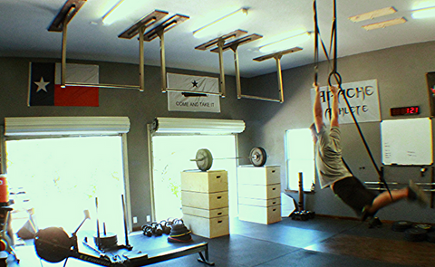 Kipping on wood gymnastics rings in a garage gym (onefitwonder)