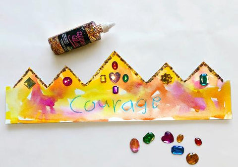 Paper crown with the word courage and watercolors, glitter glue, and gems