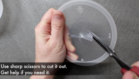 Sharp scissors cutting outline in plastic lid