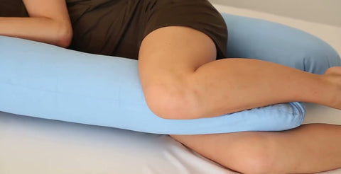 woman using blue colored pregnancy pillow for leg support and leg comfort