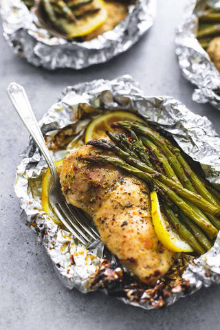 A chicken breast in foil with lemon and asparagus