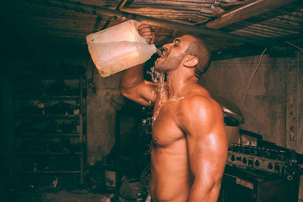 A fit man drinking from a jug of water 