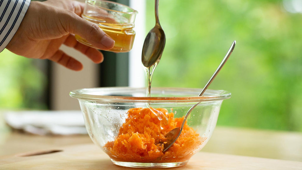 pouring honey into carrot salad dressing