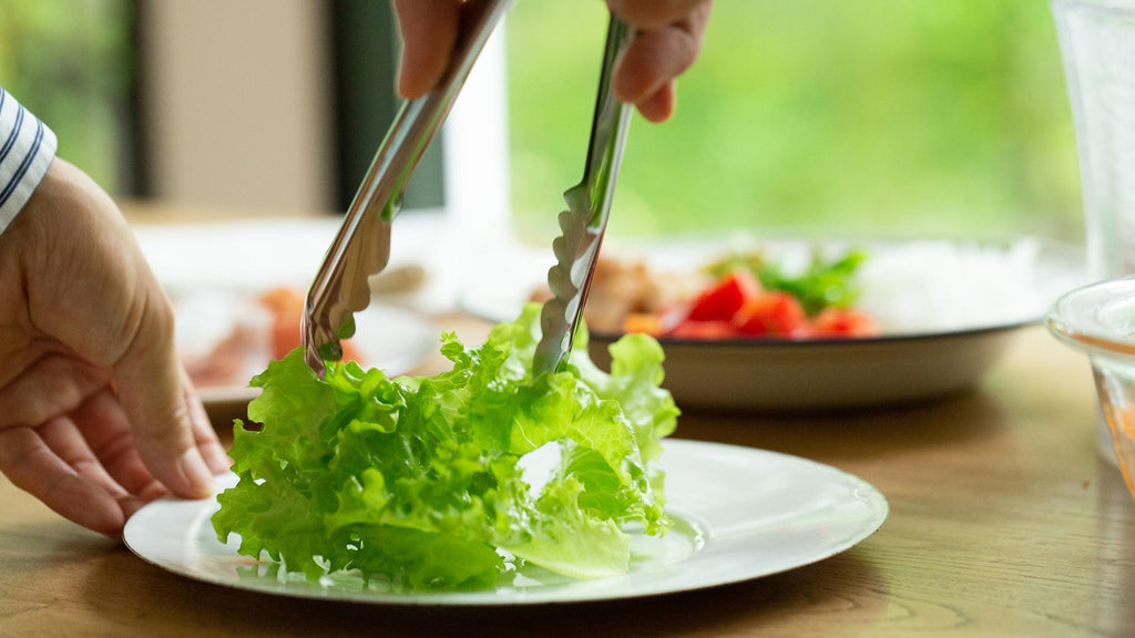 placing lettuce into bowl for carrot honey salad dressing