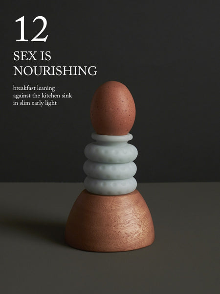 Image of a brown egg resting atop an Ohnut. "12. Sex is nourishing—breakfast leaning against the kitchen sink in slim early light."