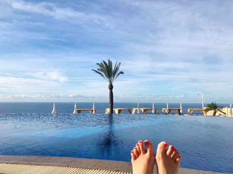 Infinity pool with the ocean and a palm tree in the background