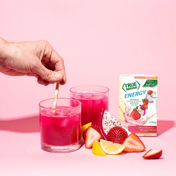 Two glasses filled with True Lemon Energy Strawberry Dragonfruit surrounded by fresh fruit.