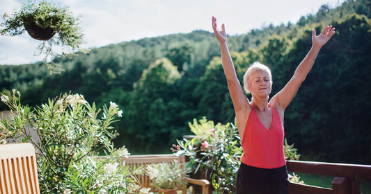 an older woman reaching arms up on outdoor balcony