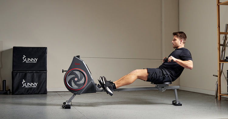 man exercising on rowing machine